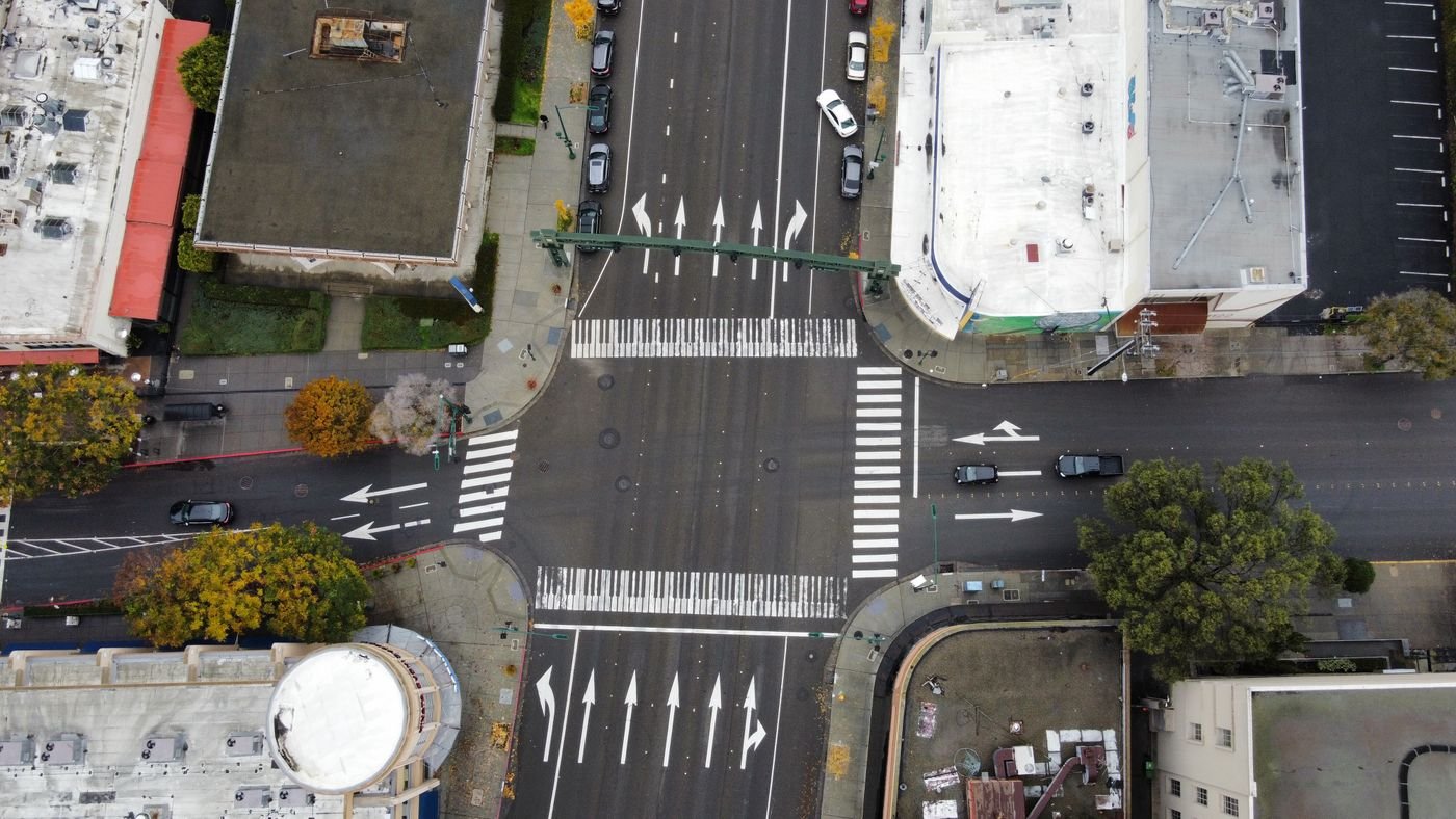 Aerial view of a city road intersection with crosswalks and cars