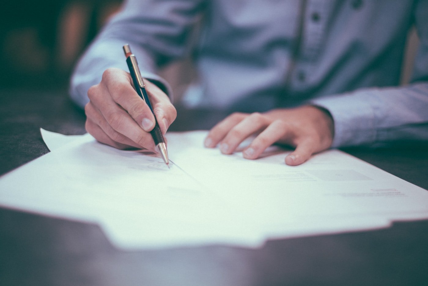 A person completing paperwork with a pen
